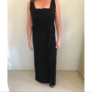 Black gown, gathered draped bodice, front slit.